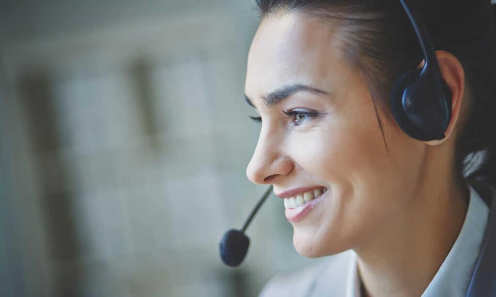 A smiling customer support representative wearing a headset.